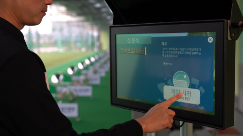 사진2) 탑트레이서 레인지 이용객이 모니터에 게임 모드를 실행시키고 있다.