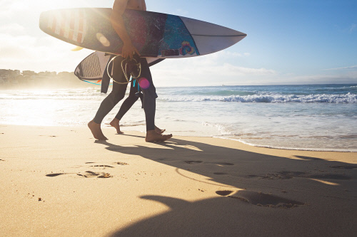 Australian surfers walking along Bondi Beach